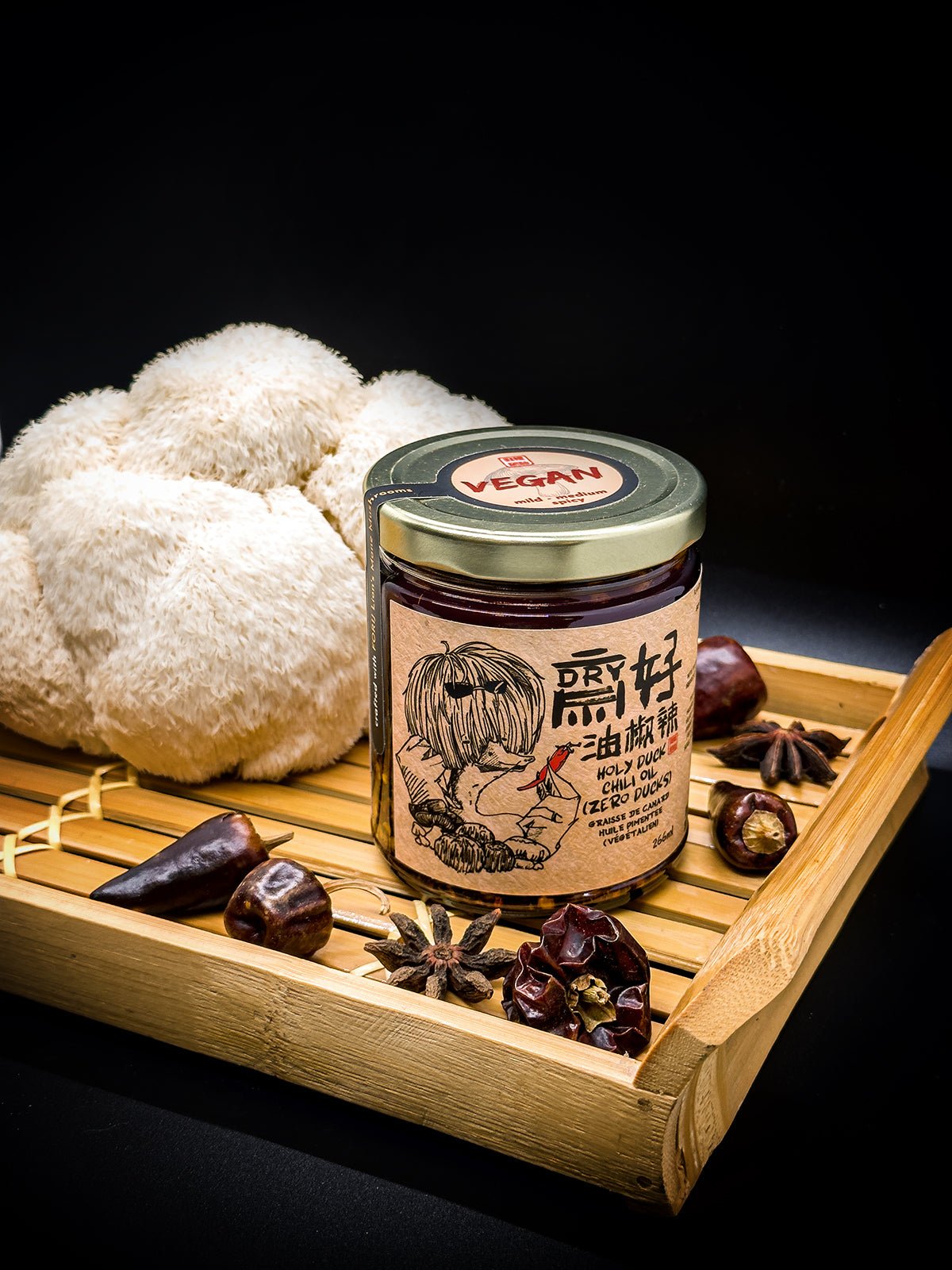 Holy Duck Zero Ducks vegan chili oil with fresh lion's mane mushroom on bamboo tray — vegan, dark background.